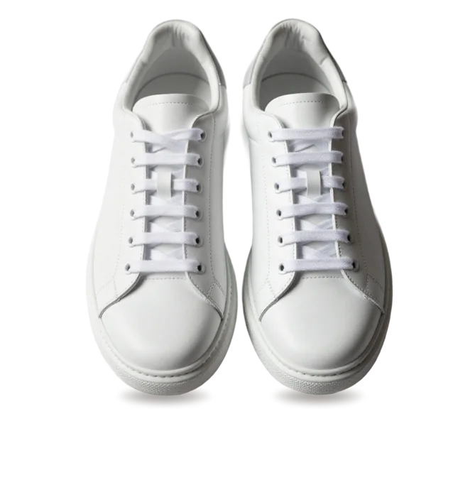 Pair of clean white leather sneakers standing on a marble pedestal