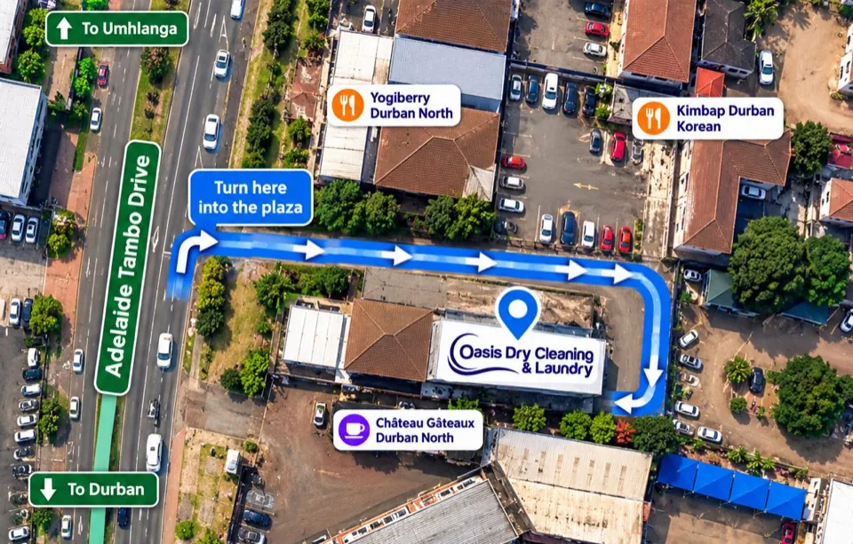 Aerial map of the Oasis Durban North branch at 66 Adelaide Tambo Drive. A blue route turns off Adelaide Tambo Drive into the plaza, runs along the lane away from the road, turns down the right-hand side of the building and ends at the rear parking behind the Oasis building, beside Château Gâteaux. Arrows show the direction of travel from the entrance to the rear parking. Labels mark Adelaide Tambo Drive, the way to Umhlanga and to Durban, and nearby shops.